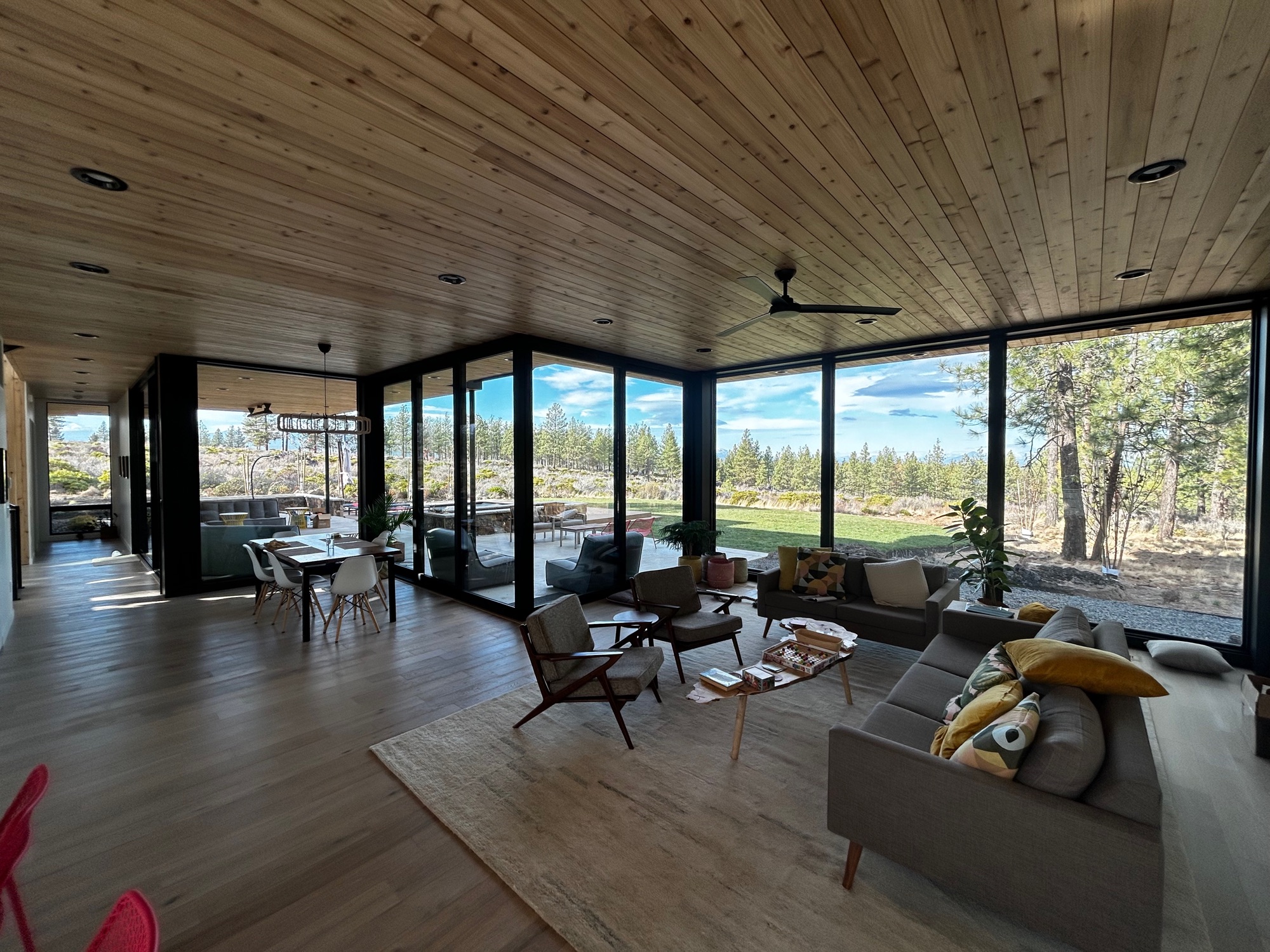 Living room with wood ceiling, exposed beams, and walls of glass